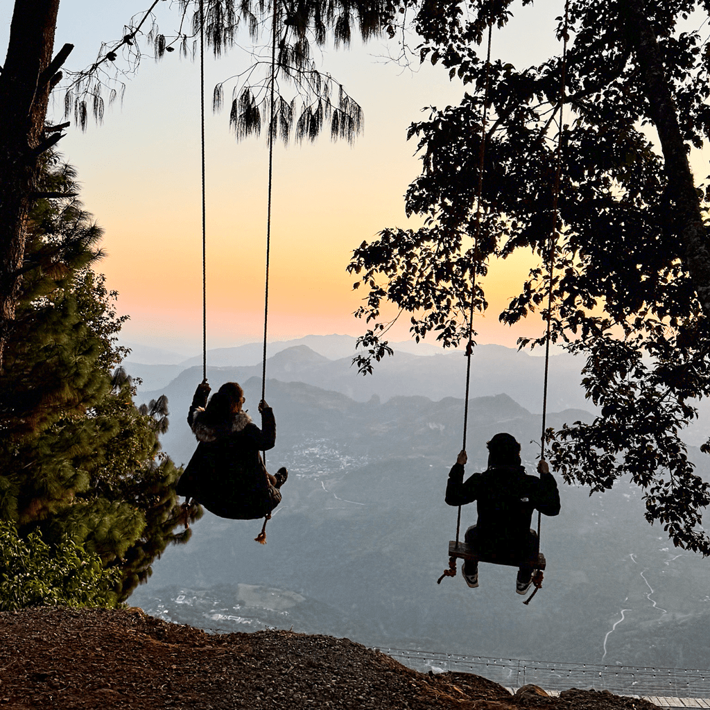 Danni y Mike en columpios viendo el atardecer sobre las montañas