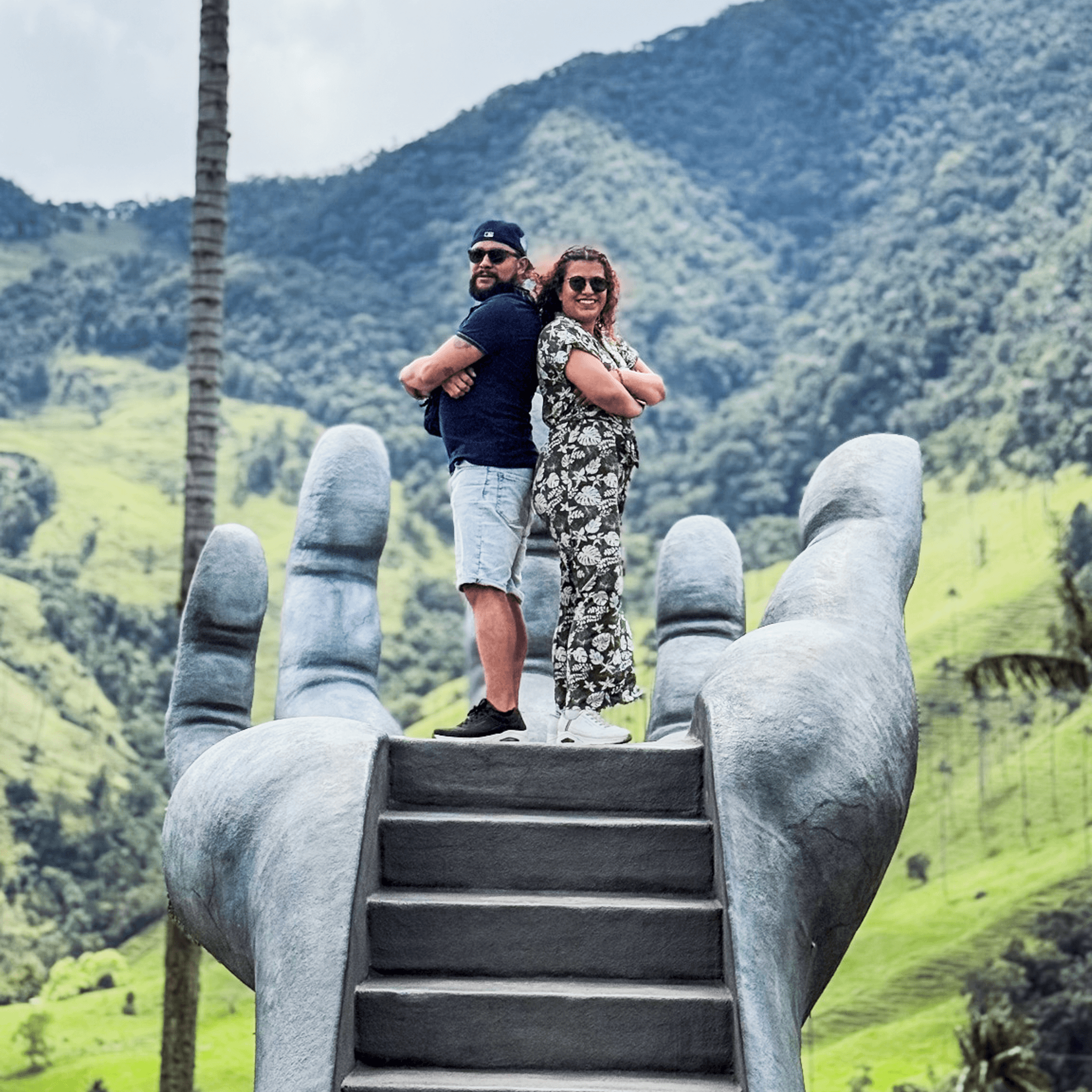 Danni y Mike en un mirador con esculturas gigantes entre montañas